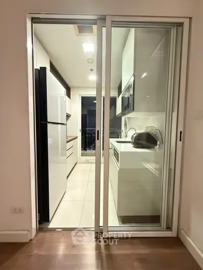 Modern kitchen with sleek appliances and open layout leading to balcony view.