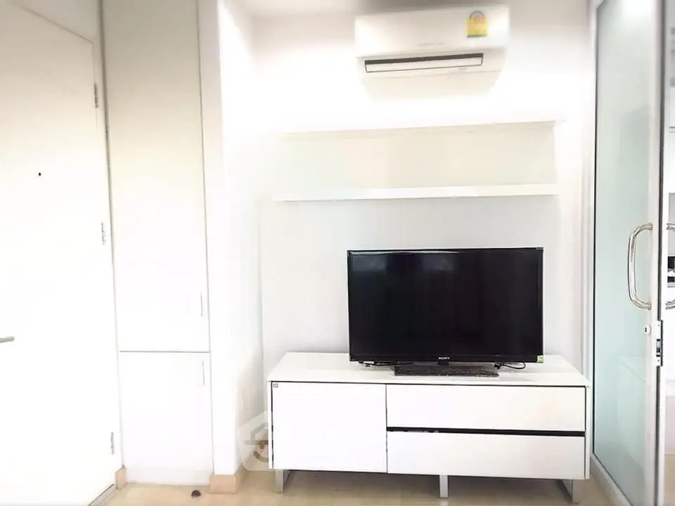 Modern living room with sleek white furniture and wall-mounted air conditioner.