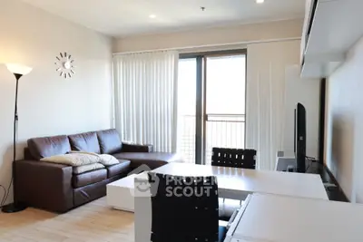 Modern living room with leather sofa, stylish decor, and natural light from large windows.