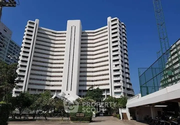Stunning high-rise building with modern architecture and lush greenery in urban setting.