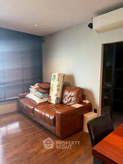 Cozy living room with leather sofa and wooden flooring, ideal for relaxation.