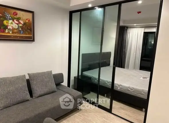 Modern apartment with glass partition separating living room and bedroom, featuring stylish decor.
