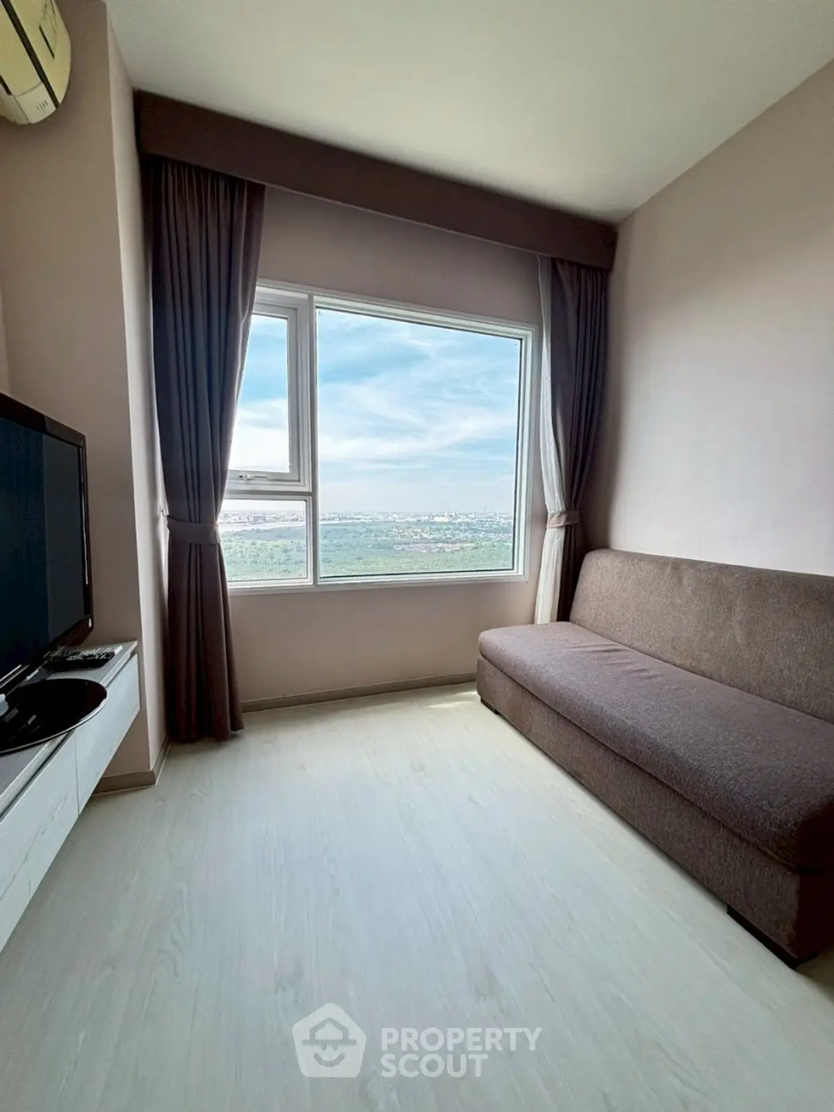 Cozy living room with large window offering stunning city view, modern sofa, and sleek TV setup.