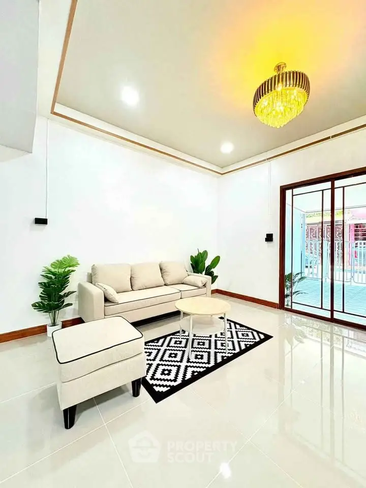 Elegant living room with modern chandelier and cozy seating area, featuring a stylish rug and natural light.