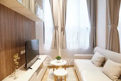 Cozy modern living room with natural light, stylish sofa, and sleek TV setup.