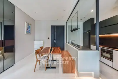 Modern kitchen with sleek design and open layout, featuring wooden dining table and contemporary appliances.