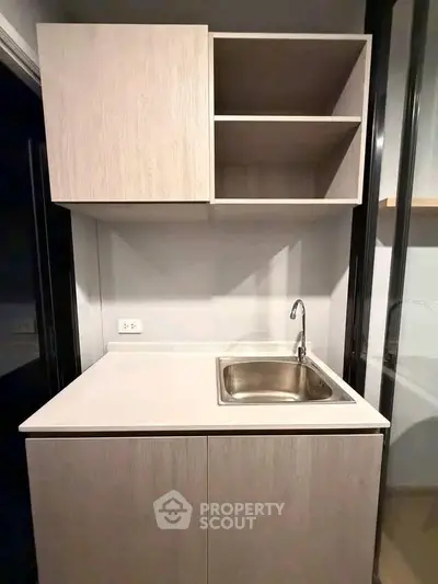 Compact modern kitchen with sleek cabinetry and stainless steel sink, perfect for efficient cooking.