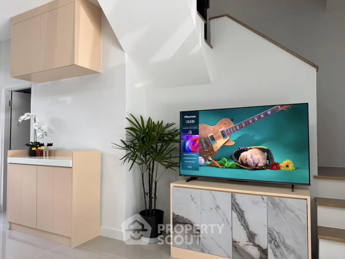 Modern living room with stylish TV setup and elegant cabinetry under staircase