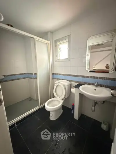 Modern bathroom with shower, toilet, and sink in a sleek design.