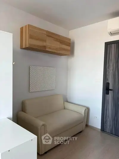 Cozy living room with modern beige sofa and wooden wall cabinet, perfect for small spaces.