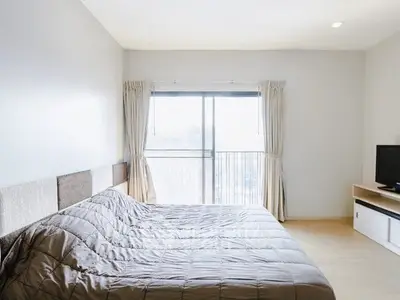 Spacious bedroom with large window and modern decor in a stylish apartment.