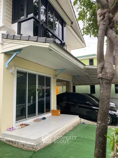 Charming two-story house with carport and lush greenery