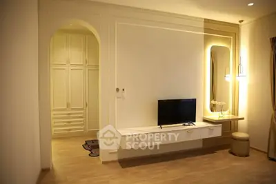 Elegant living room with modern TV setup and stylish lighting, featuring built-in storage and warm wooden flooring.