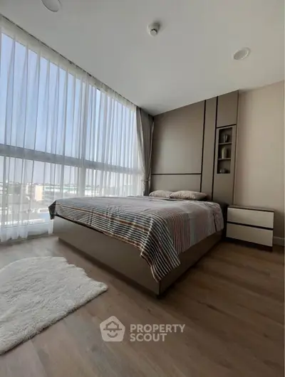 Modern bedroom with large windows and stylish decor, offering a bright and inviting atmosphere.