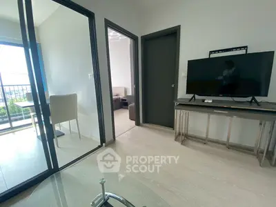 Modern living room with TV and balcony view, sleek design and natural light.