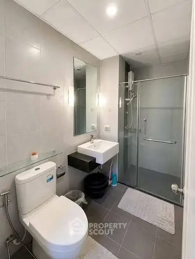 Modern bathroom with glass shower and sleek fixtures in a contemporary apartment.