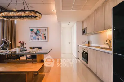 Modern kitchen with open layout and stylish dining area featuring wooden table and elegant chandelier.