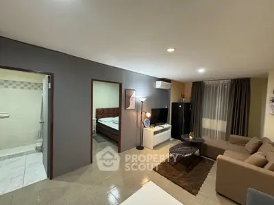 Spacious living room with modern decor and adjacent bedroom in a cozy apartment.