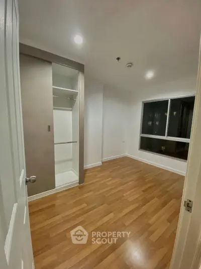 Spacious bedroom with wooden flooring and built-in closet, perfect for modern living.