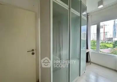 Bright bedroom with large wardrobe and city view, perfect for urban living.