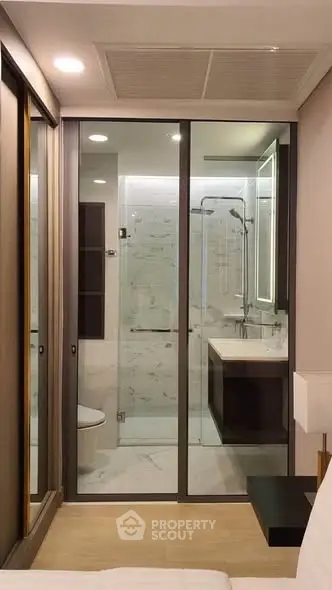 Modern bathroom with glass shower enclosure and sleek vanity in a contemporary apartment.