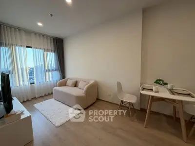 Modern living room with cozy sofa and dining area, featuring large window and stylish decor.