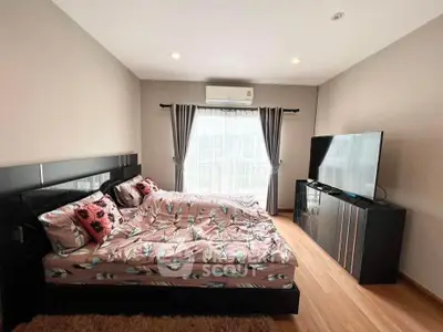 Modern bedroom with stylish decor and large TV, featuring elegant curtains and cozy bedding.