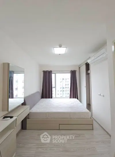 Spacious bedroom with modern decor and large window offering city views.
