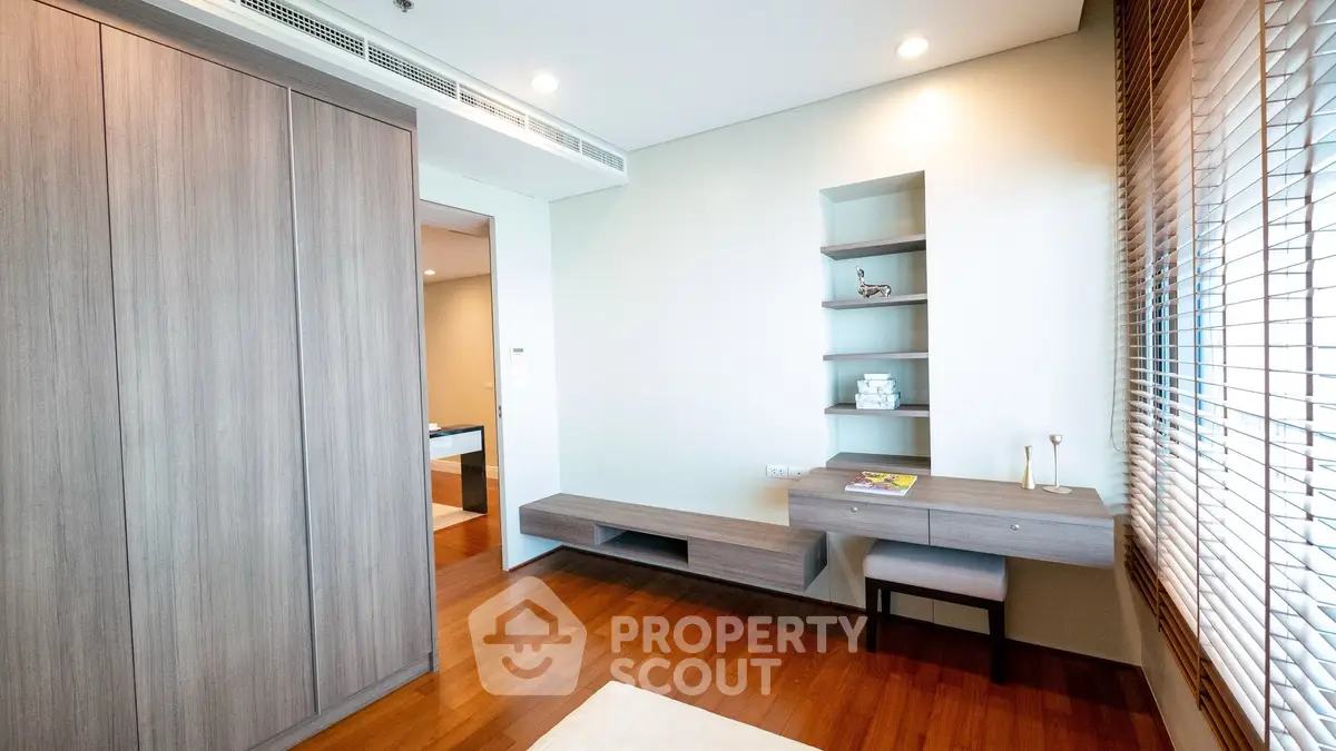 Modern study room with wooden flooring and built-in shelves in a stylish apartment.