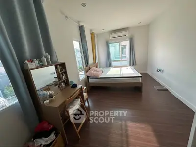 Spacious bedroom with modern furnishings and large windows for natural light.