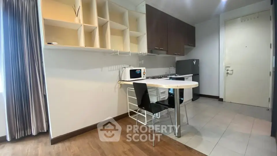 Modern kitchen with open layout, featuring sleek cabinets, dining area, and appliances in a cozy apartment setting.