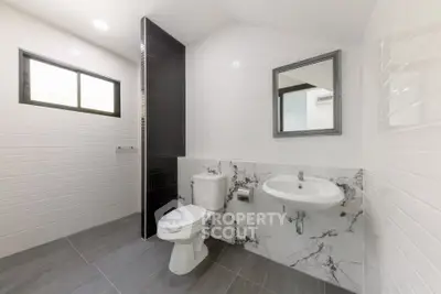 Modern bathroom with sleek design, featuring a toilet, sink, and stylish tile work.