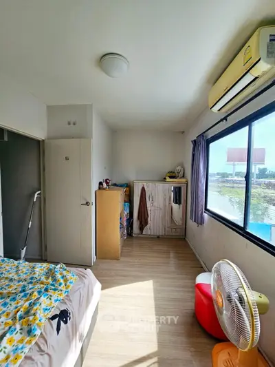 Cozy bedroom with natural light, featuring wooden flooring and modern air conditioning.