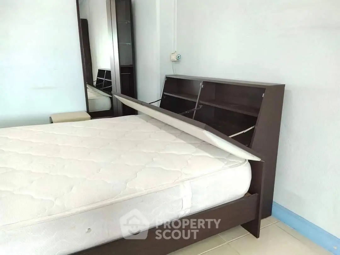 Spacious bedroom with modern bed and storage headboard, ideal for comfort and organization.