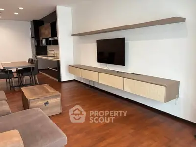 Modern living room with sleek furniture and wall-mounted TV, featuring elegant wooden flooring.