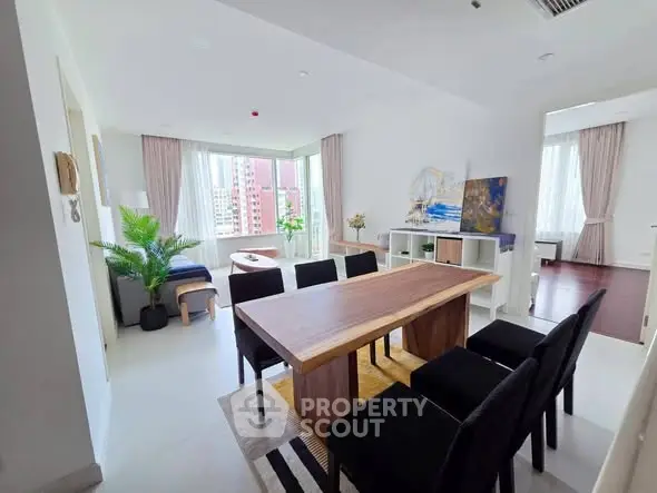 Spacious modern living room with elegant dining area and large windows offering city views.