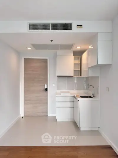 Modern compact kitchen with sleek white cabinetry and integrated appliances