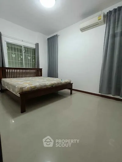 Spacious bedroom with modern decor and large window for natural light.