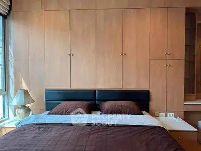 Luxurious bedroom with elegant wooden cabinetry and cozy bedding in modern apartment.