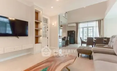 Spacious living room with modern decor and natural light, featuring a stylish wooden coffee table and wall-mounted TV.