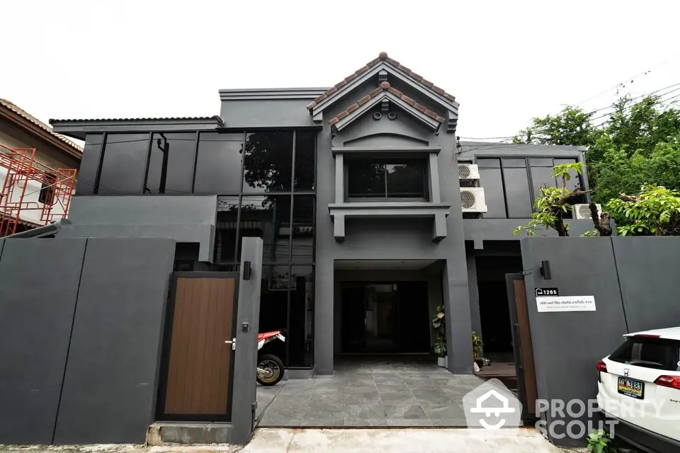 Modern two-story house with sleek gray facade and gated entrance