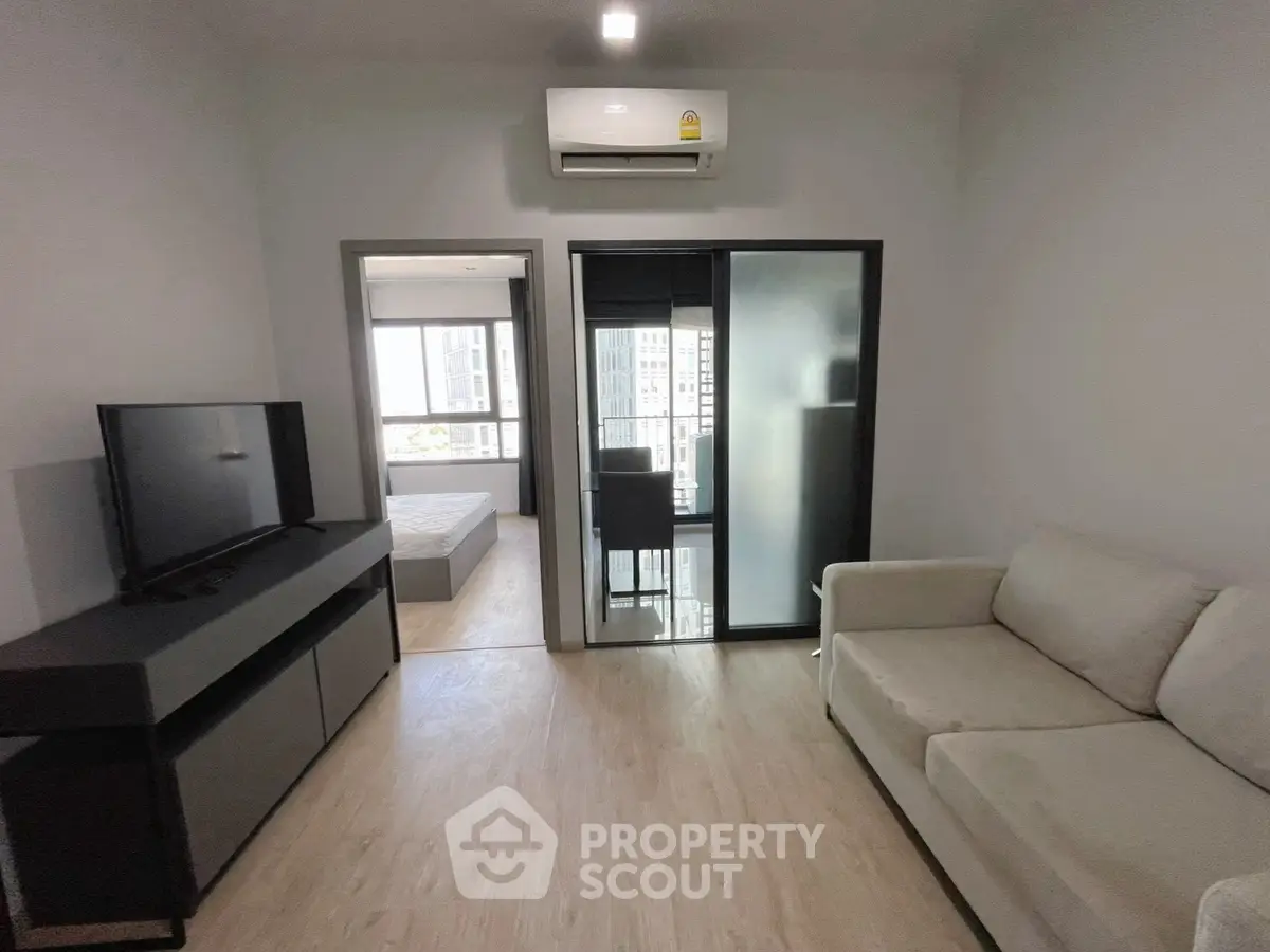 Modern living room with sleek design and natural light, featuring a cozy sofa and flat-screen TV.