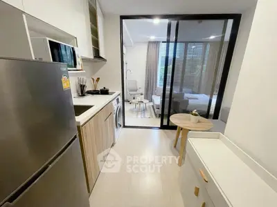 Modern kitchen with sleek appliances and open layout leading to a cozy living area.