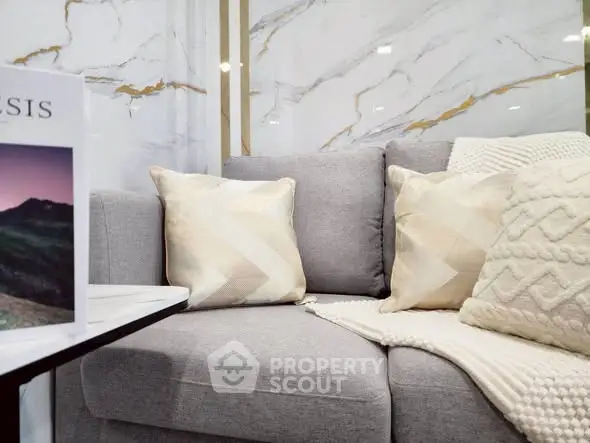 Luxurious modern living room with elegant marble wall and cozy gray sofa adorned with plush cushions.
