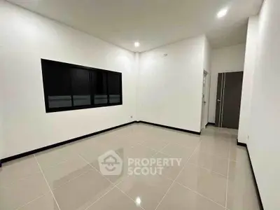 Spacious empty room with tiled flooring and large window, ideal for customization.