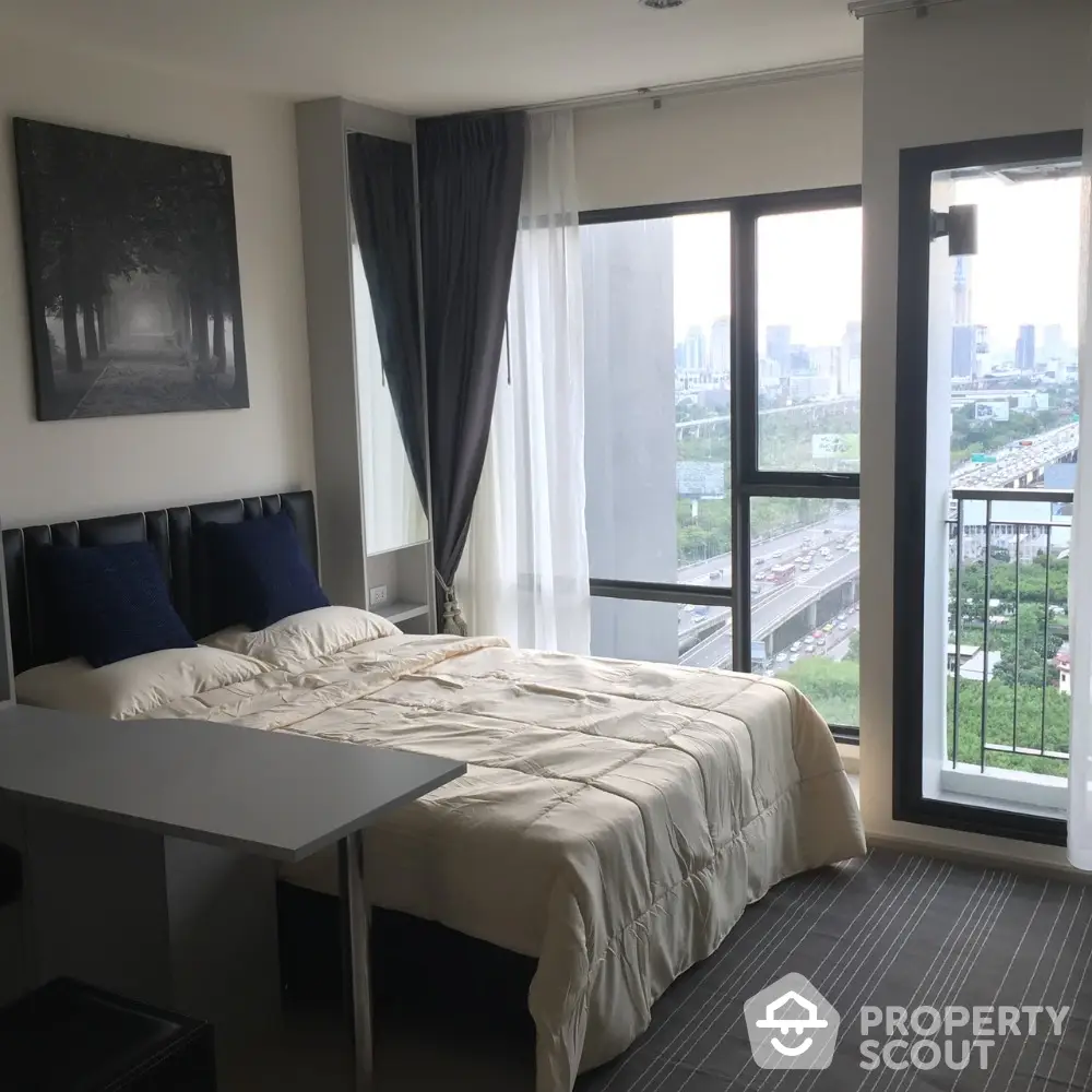 Modern bedroom with city view and balcony access in high-rise apartment