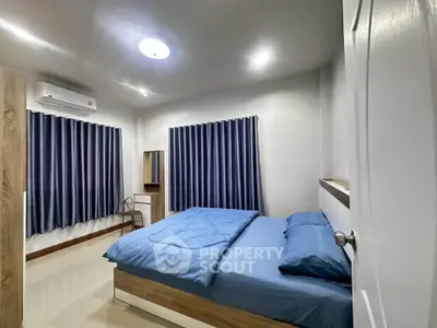 Modern bedroom with blue bedding, air conditioning, and stylish curtains.