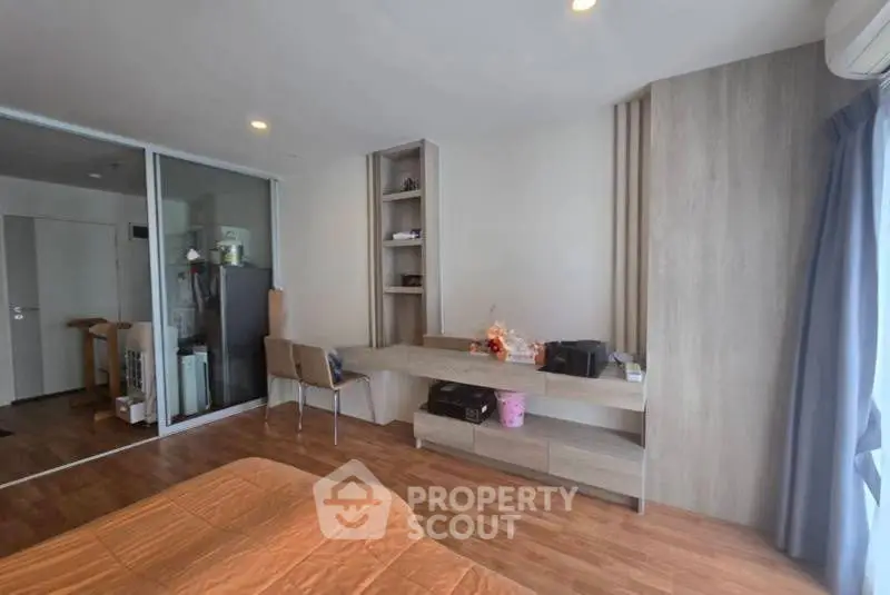 Modern bedroom with wooden flooring and built-in desk, featuring ample natural light.