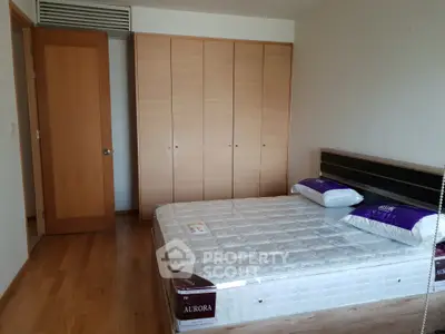 Spacious bedroom with wooden flooring and large wardrobe, featuring a comfortable bed with new mattress.