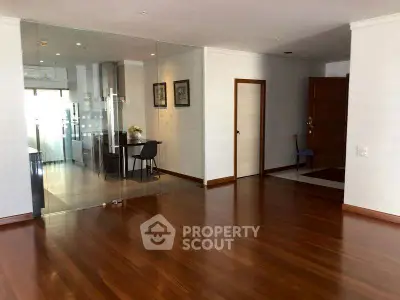 Spacious open-plan living area with wooden flooring and glass partition.